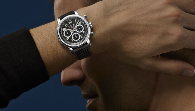 Man wearing a Chopard Mille Miglia chronograph watch with black dial and rubber strap